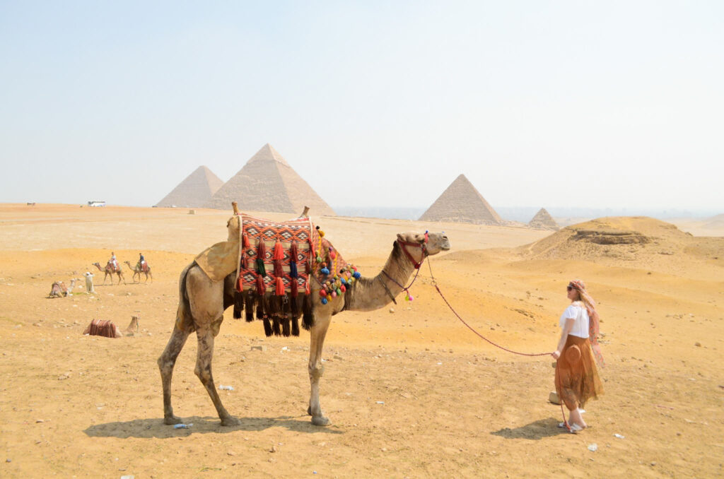 woman and camel in front of the pyramids of giza egypt