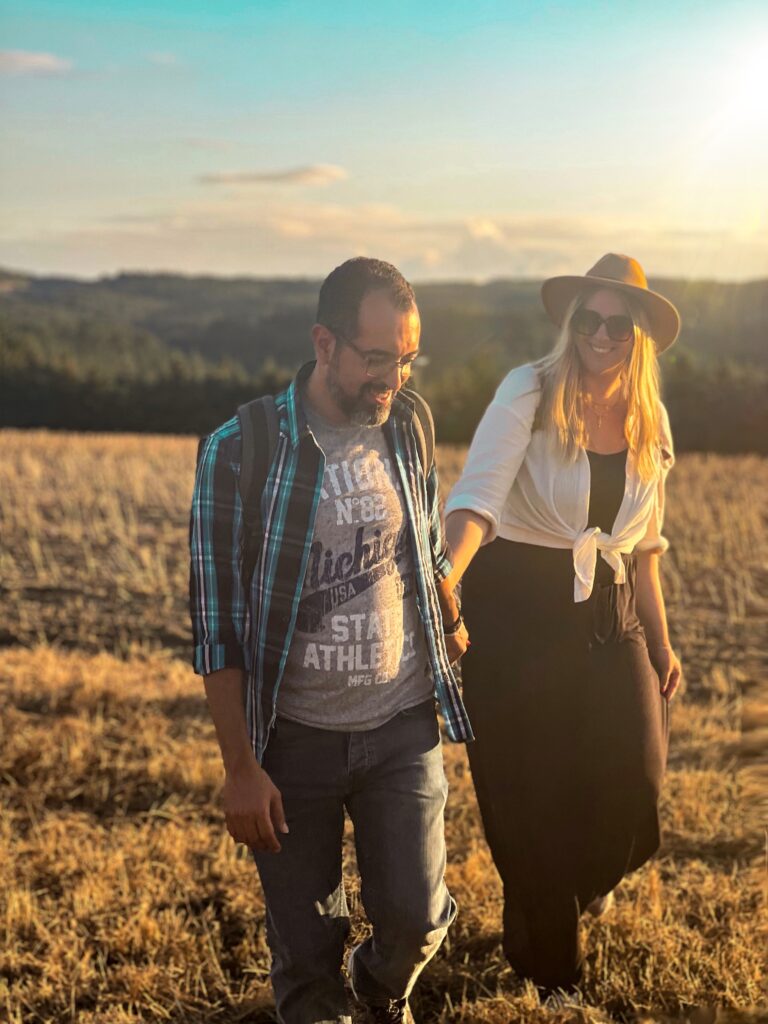 Couple on a field holding hands while sunset, golden hour