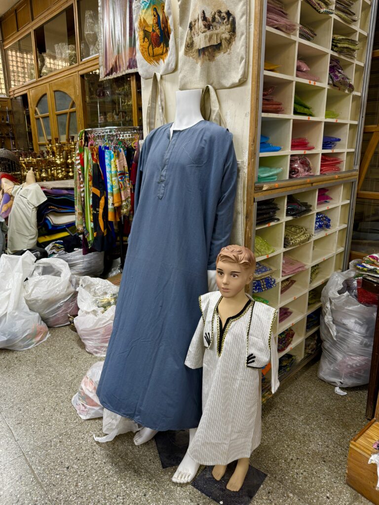 men and kid clothing in a traditional maket in egypt showing a galabeya