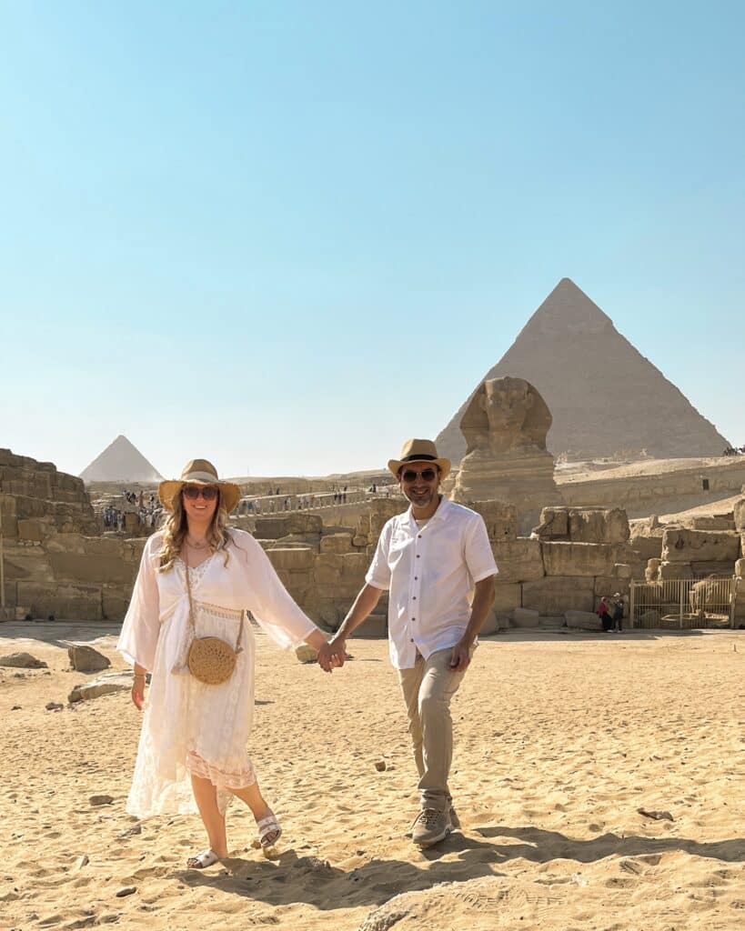 couple walking in front of the sphinx and pyramids of giza egypt