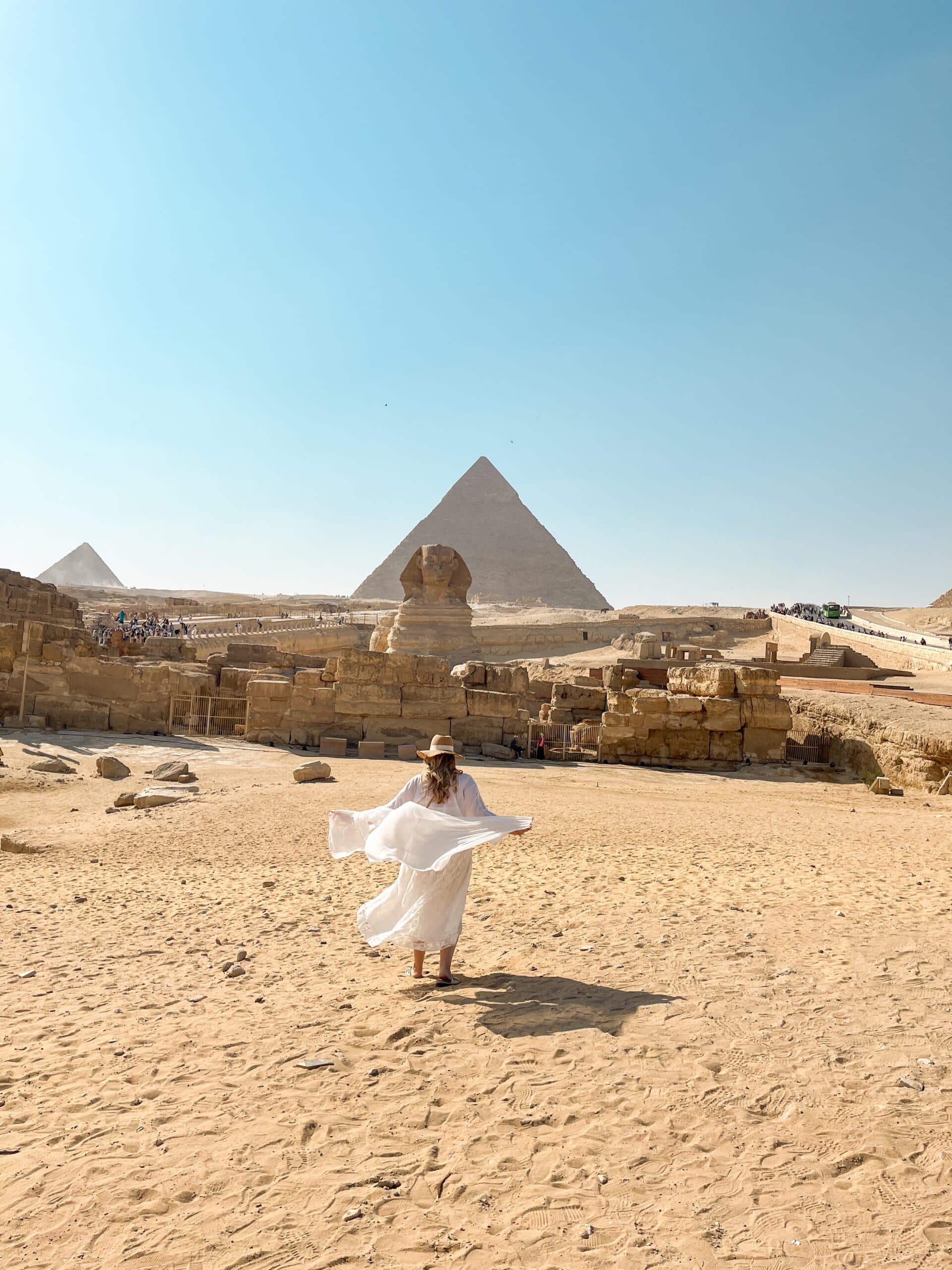 woman in white dress in front of sphinx and pyramids giza egypt